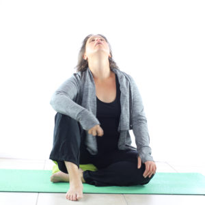 Loetitia Monge assise sur un tapis de yoga vert et respirant vers le ciel